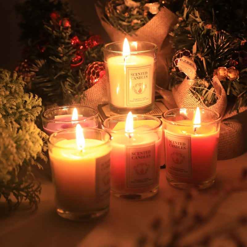Lit Delphy scented candles with warm glow, surrounded by festive greenery, creating a romantic Valentine's Day ambiance