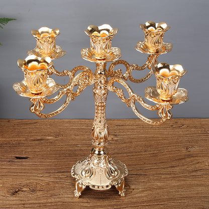 A luxurious gold 5-arm zinc alloy candelabra with intricate floral embossed patterns on a wooden surface.