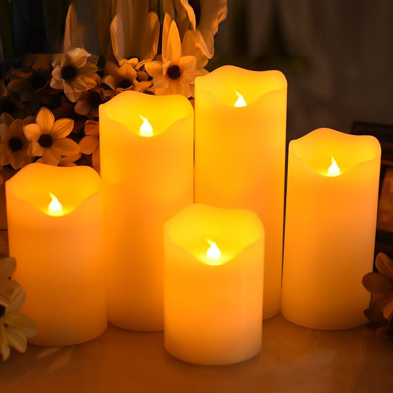 A group of five wave mouth LED electronic pillar candles of varying heights glowing with warm yellow light.